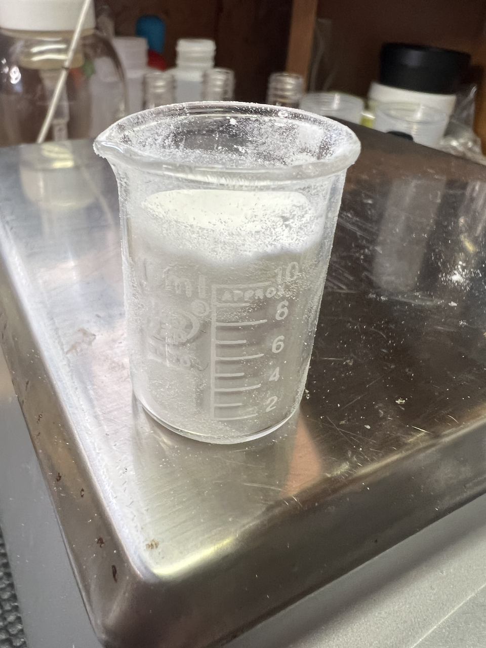 A beaker with a white powder - an emulsifier called Eumulgin - sits on the edge of a digital scale.