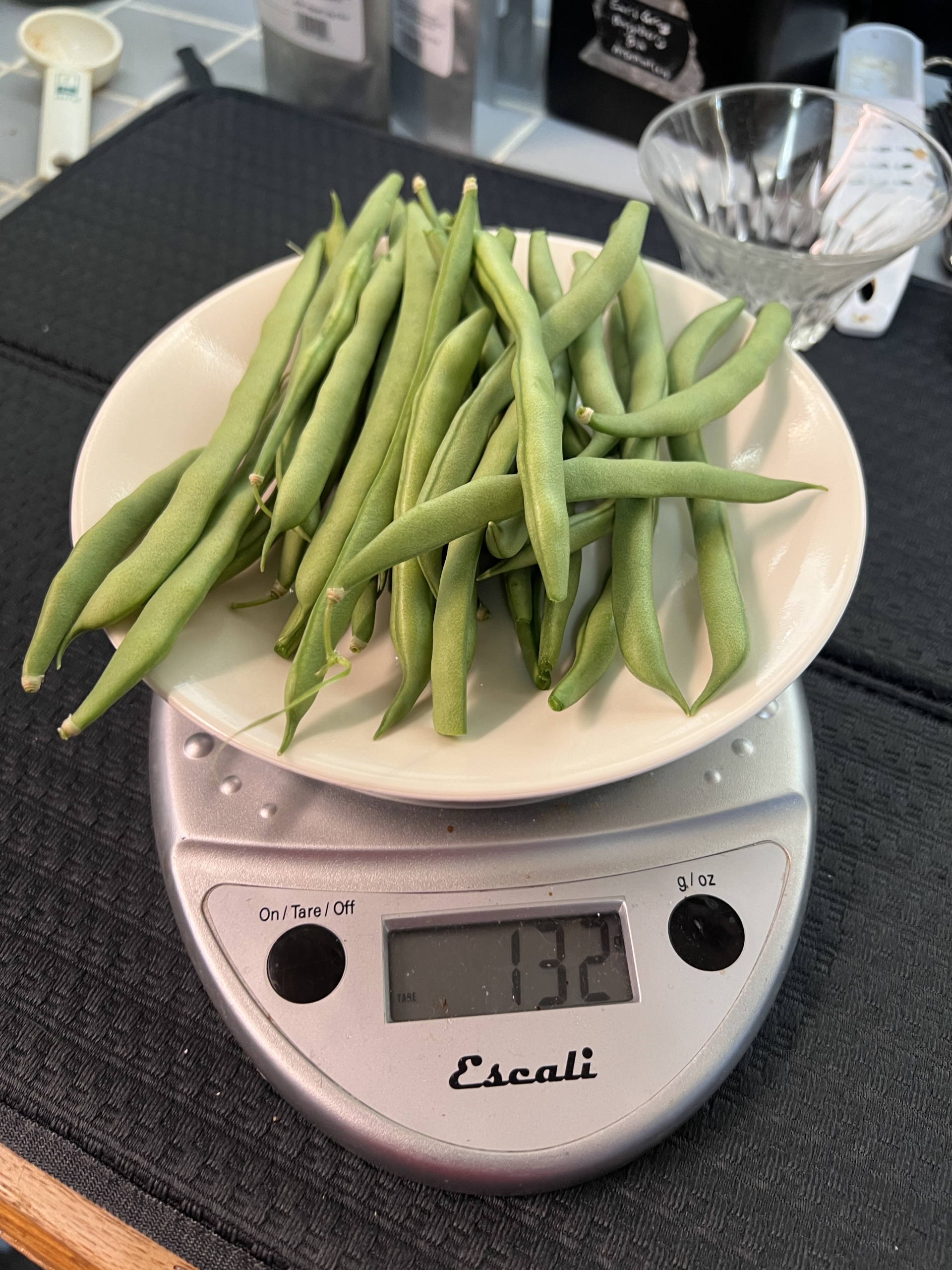 Plate with green beans on it on a digital scale. They weigh 132 grams.