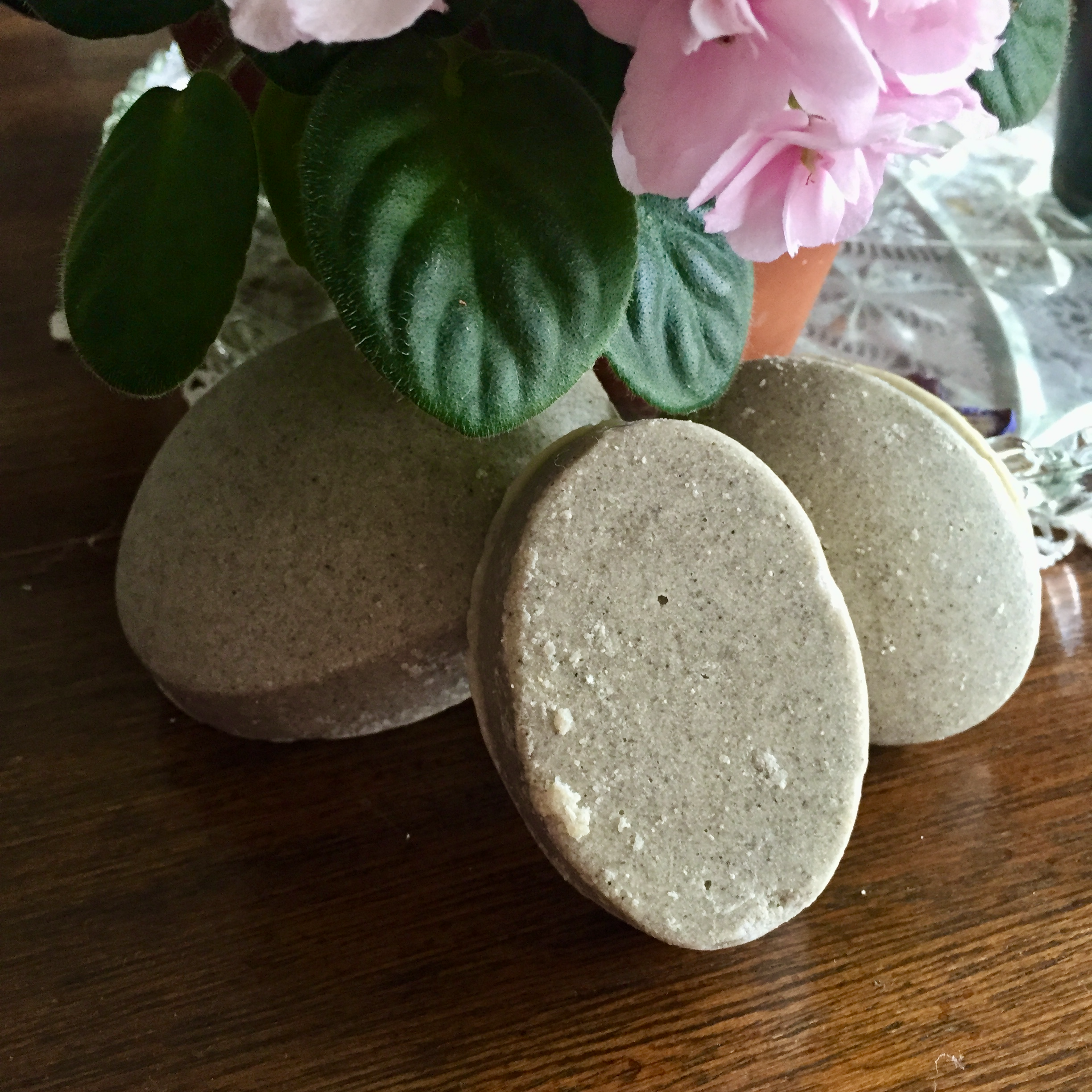 Three foot scrub bars - oval bars made with various butters and pumice - sit under a pink violet.